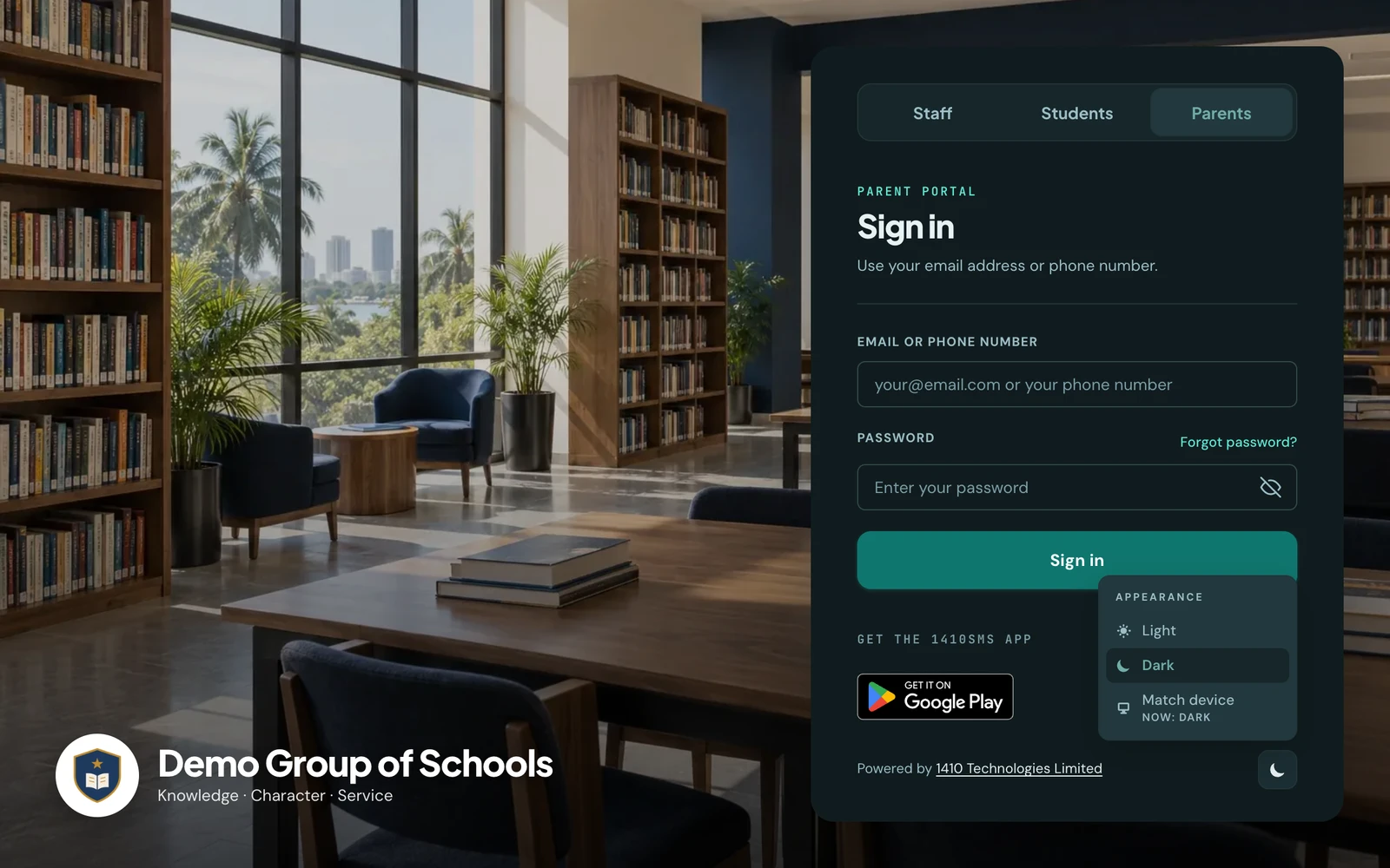 The parent sign-in page of Demo Group of Schools in dark mode, in the floating card layout, with the library photo slightly toned down behind a dark sign-in card. At the foot of the card, beside Powered by 1410 Technologies Limited, the appearance menu is open, offering Light, Dark, selected, and Match device.